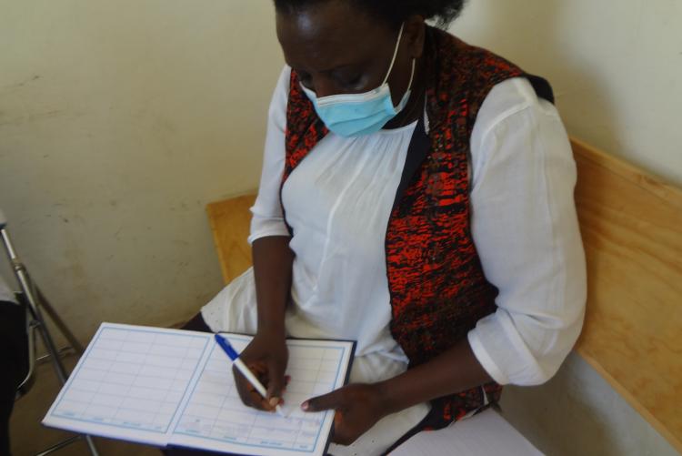 Mrs Helen Nzainga signs the visitors book at  the Assistant County Commissioner's (ACC) office