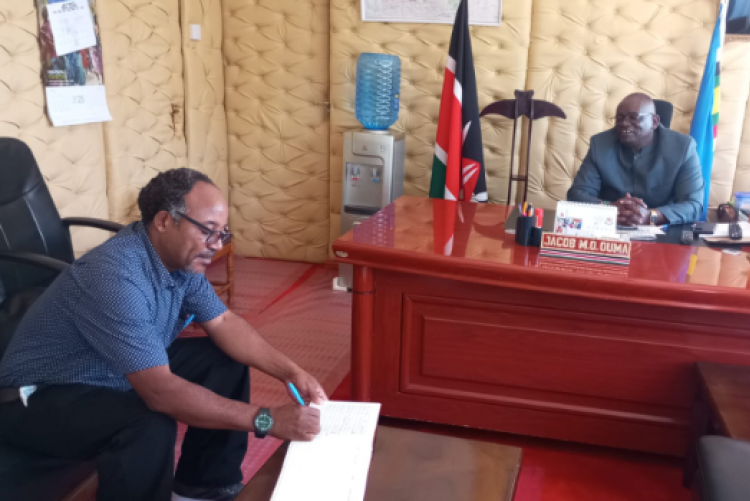Eng. Murimi signs the visitors book at the County Commissioner's office